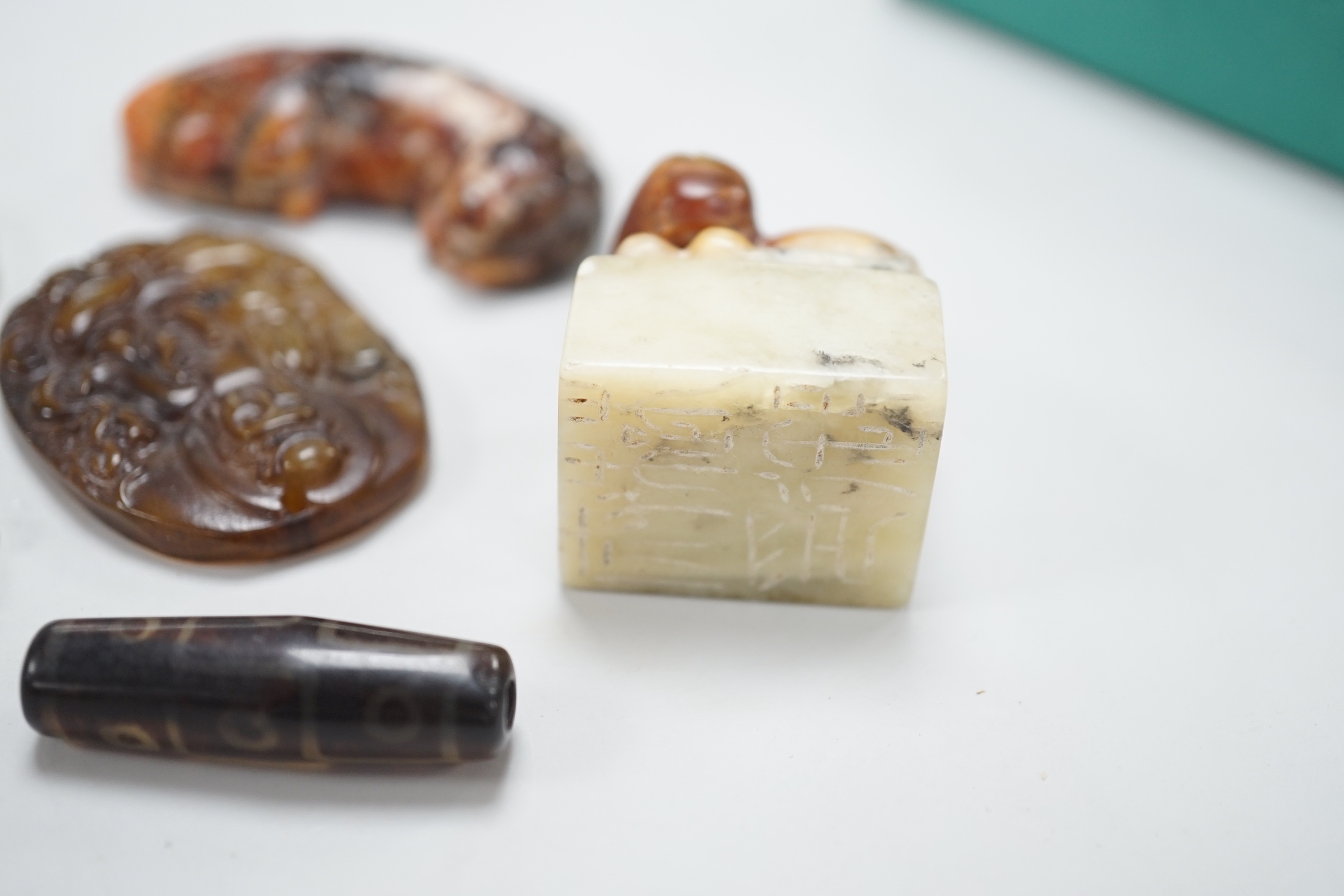 A Chinese pale celadon jade bi disc, a jade carving of the character ‘Shou’ , two hardstone carvings of creatures, an agate pendant of Guanyin in Tang dynasty style and a stained glass , bead in Tibetan style (6), disc 4
